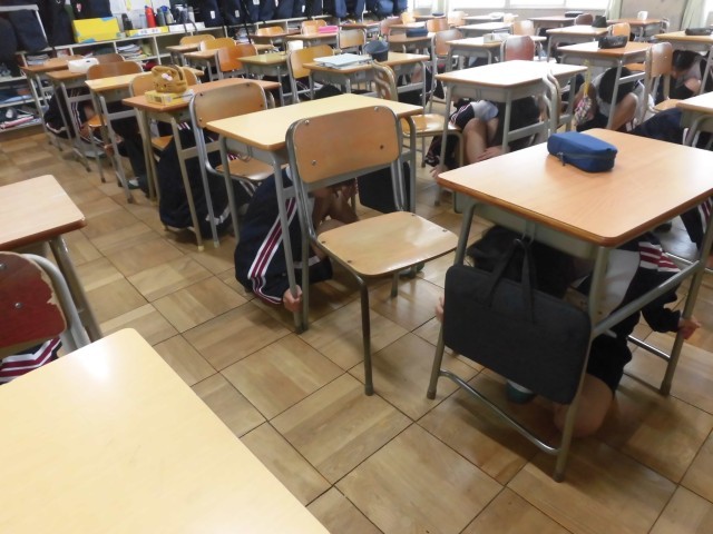 机の下に隠れました